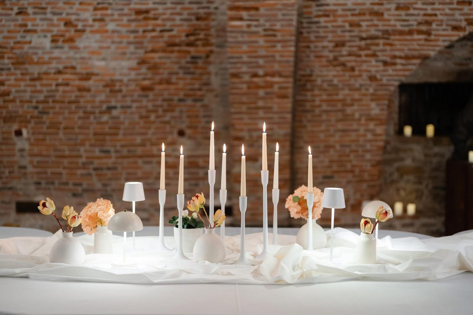 A white tablescape with tall candles at an event venue