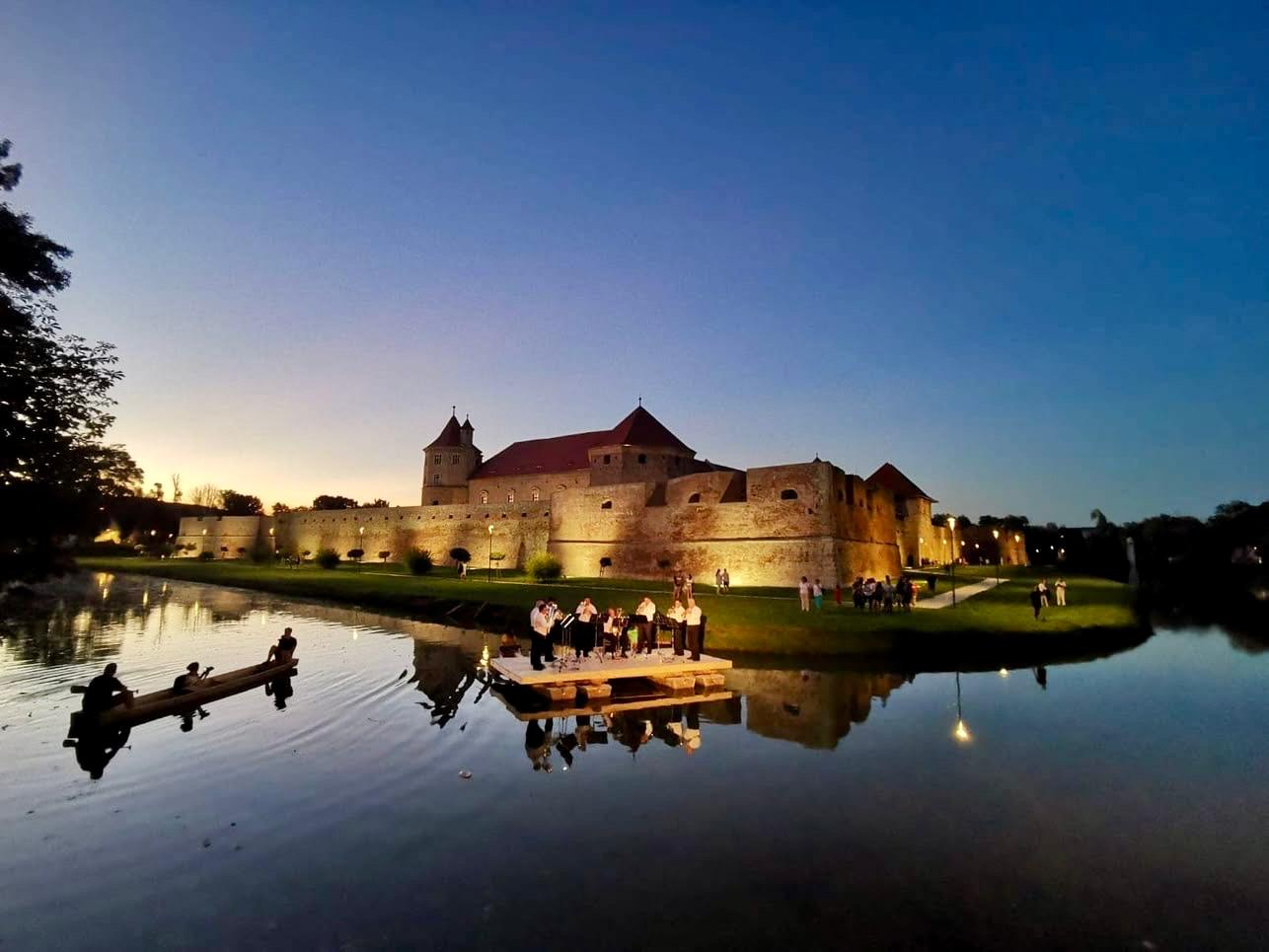 An evening event on the lake below a floodlit fortress
